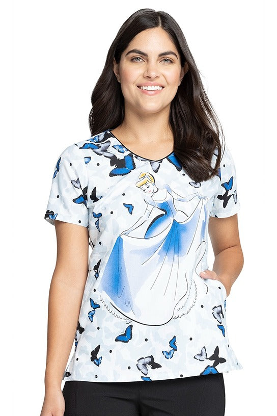 A young female LPN wearing a Tooniforms Women's V-Neck Print Scrub Top in "All a Flutter" featuring a relaxed V-neckline.