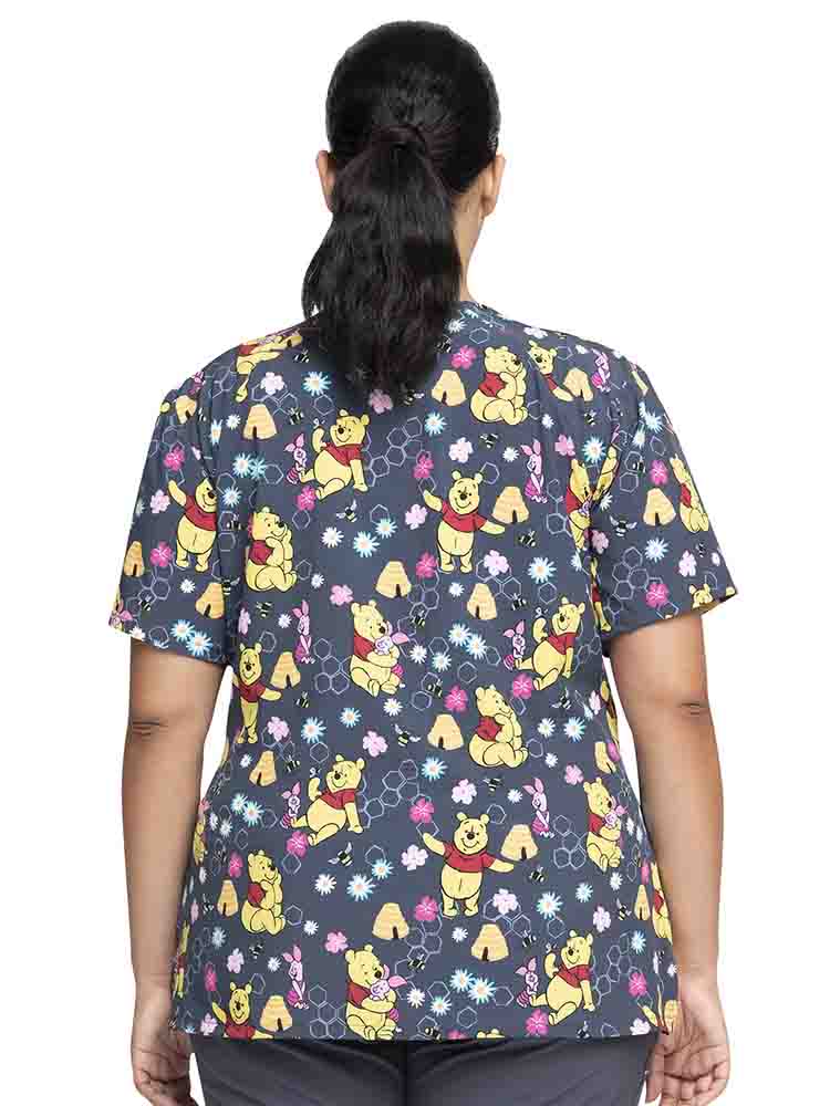 Young female healthcare professional wearing a Tooniforms Women's V-Neck Print Scrub Top in "Bee's Knees" featuring front & back yokes to ensure a flattering shape.