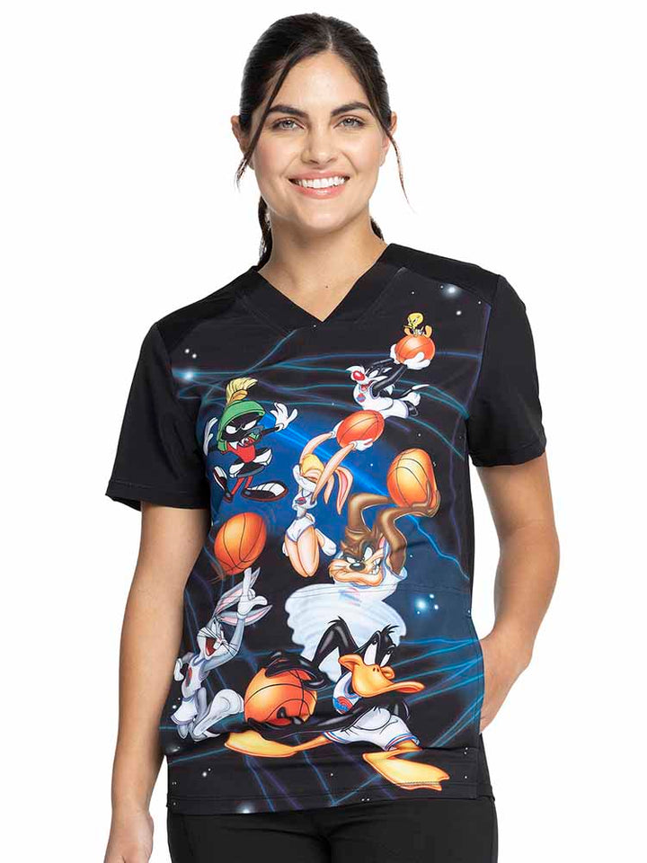 Young woman wearing a Tooniforms Unisex V-Neck Print Scrub Top in "Space Jam" featuring front & back yokes for flattering shaping.