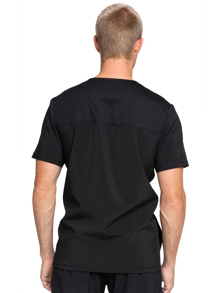 Young male healthcare professional wearing a Tooniforms Unisex V-Neck Print Scrub Top in "Space Jam" featuring mesh panels at the side for extended range of motion.