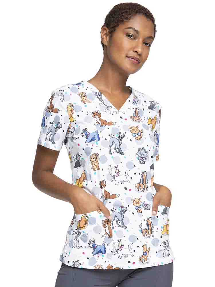 Young woman wearing a Tooniforms Women's V-Neck Print Scrub Top in Cats & Dogs featuring a modern classic fit, short sleeves & side vents to provide additional range of motion.