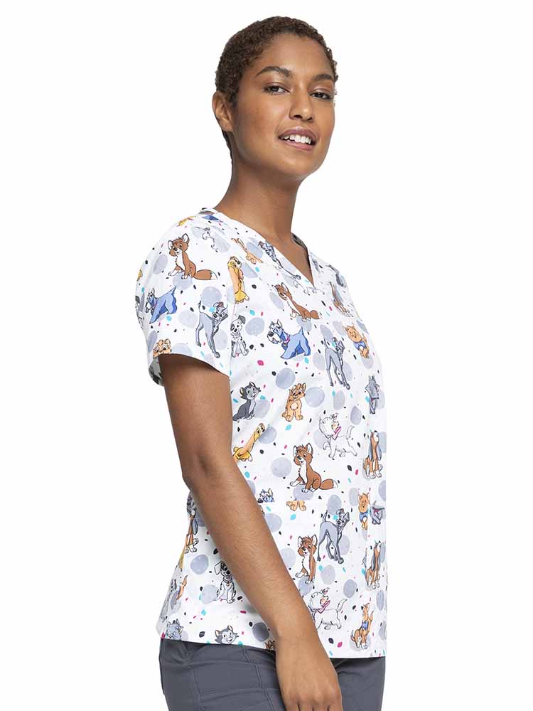 Female Healthcare Professional wearing a Tooniforms Women's V-Neck Print Scrub Top in Cats & Dogs featuring  two front patch pockets with a pen slot located on the wearer's left.