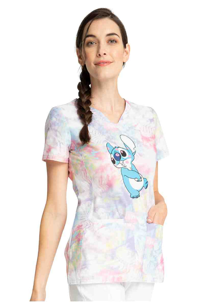 A young female Pediatrician wearing a Tooniforms Women's Shaped V-neck Print Top in "Stitch Smooches" size Medium featuring a short sleeves & a v-neckline.
