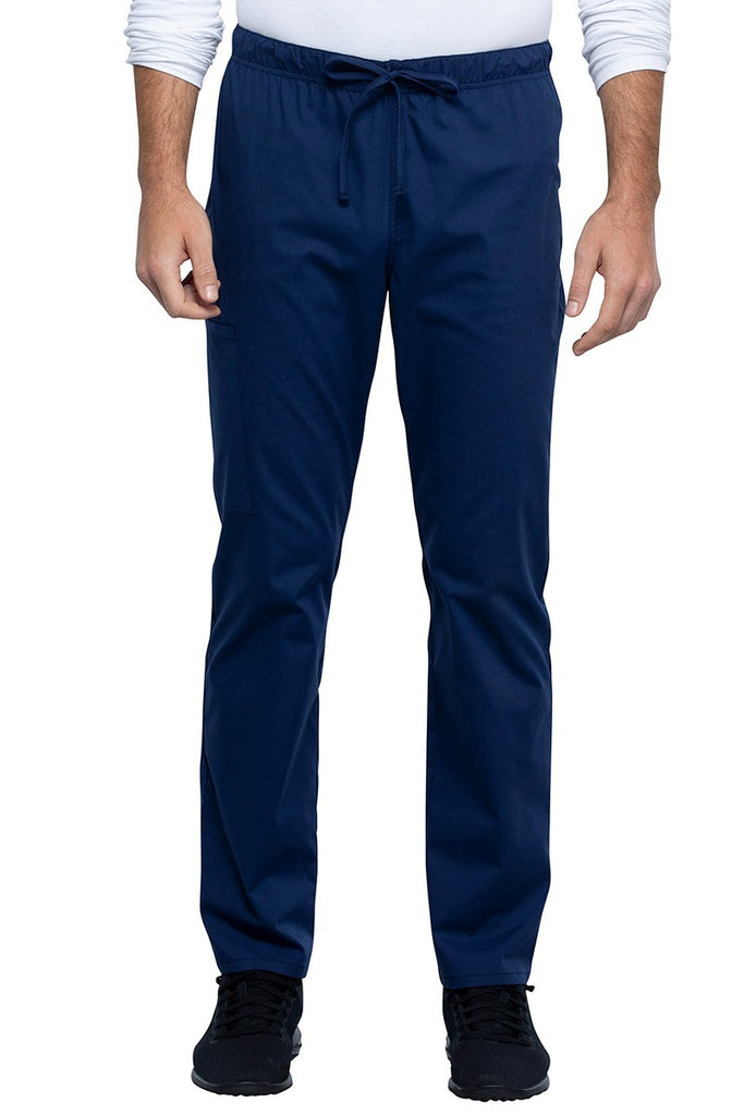 A picture of a male Nurse Practitioner wearing a Cherokee Unisex Straight Leg Scrub Pant in Navy size 2XL Tall featuring a Bi-Stretch, durable fabric.