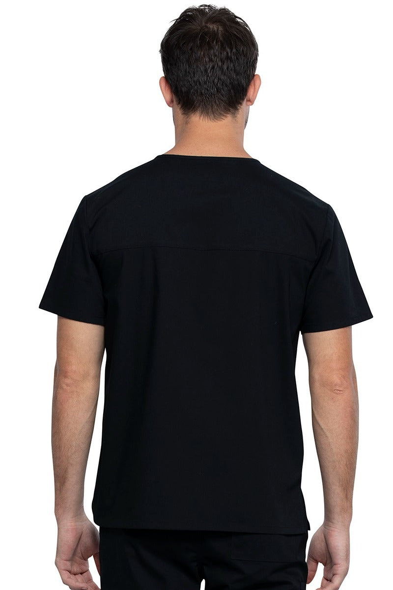 An image of a Male Medical Assistant wearing a Cherokee Unisex Tuckable V-neck Scrub Top in Black size 3XL featuring a back yoke & dolman sleeves.