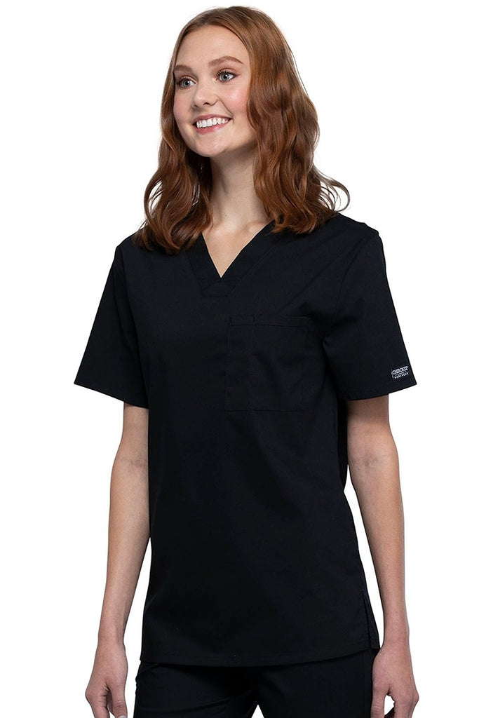 A picture of a young female Helathcare Professional wearing a Cherokee Unisex Tuckable V-neck Scrub Top in Black size Small featuring side slits for additional range of motion