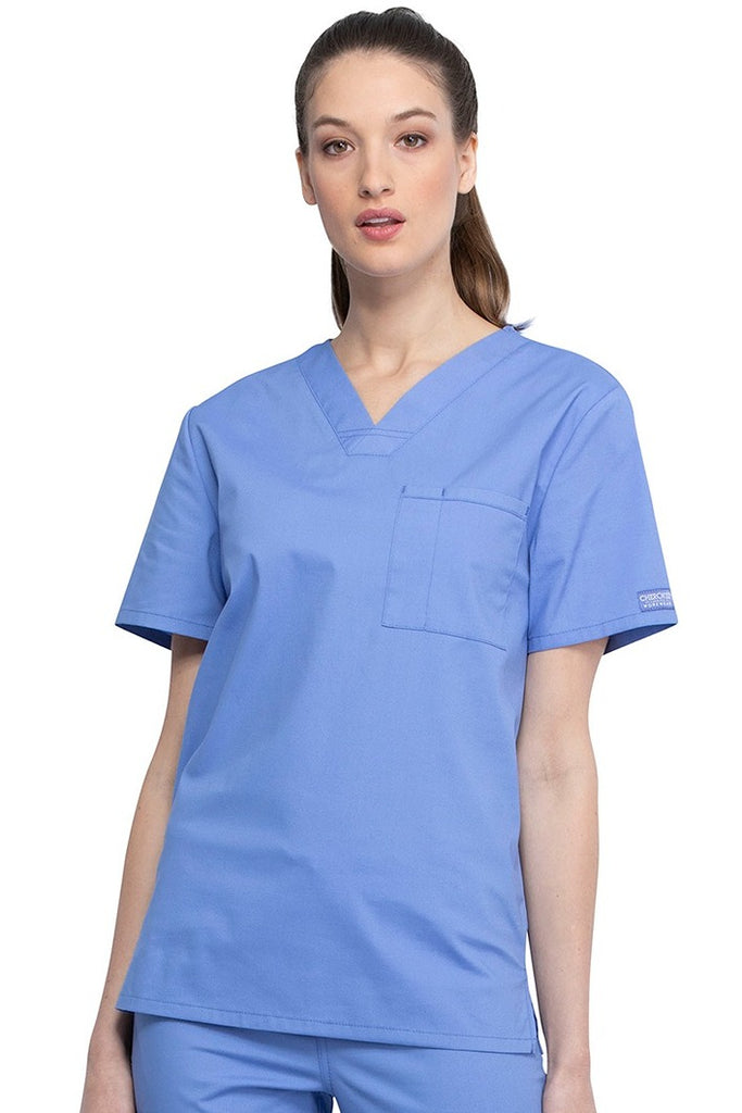 A female Nursing Assistant wearing a Cherokee Unisex Tuckable V-neck Scrub Top in Ceil Blue size Small featuring a unique Poly/Cotton/Spandex blend fabric.