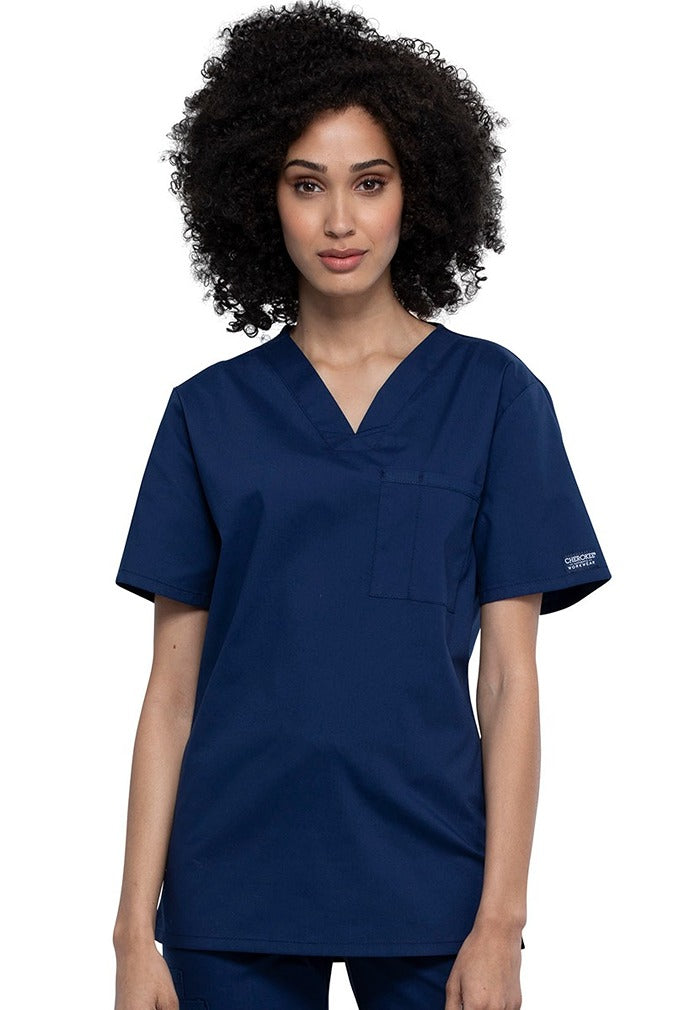 A female Nursing Assistant wearing a Cherokee Unisex Tuckable V-neck Scrub Top in Navy size Small featuring a unique Poly/Cotton/Spandex blend fabric.