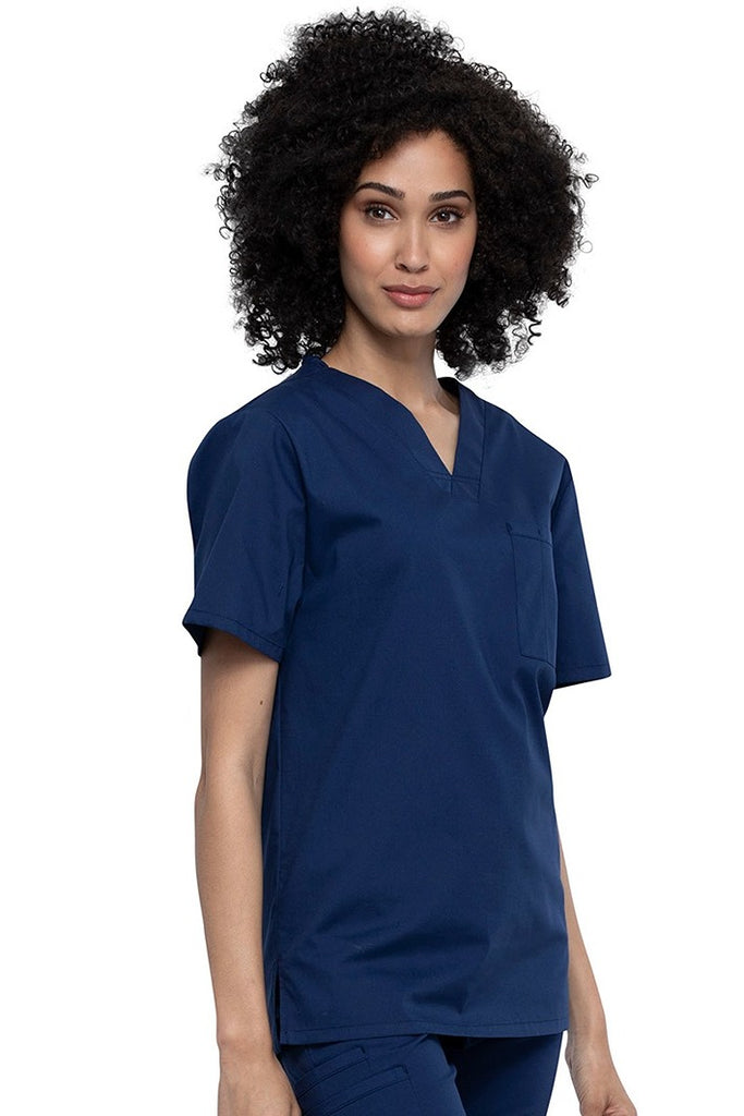 A young female Nurse Practitioner wearing a Cherokee Unisex Tuck-in V-neck Scrub Top in Navy size Large featuring short sleeves & a V-neckline.