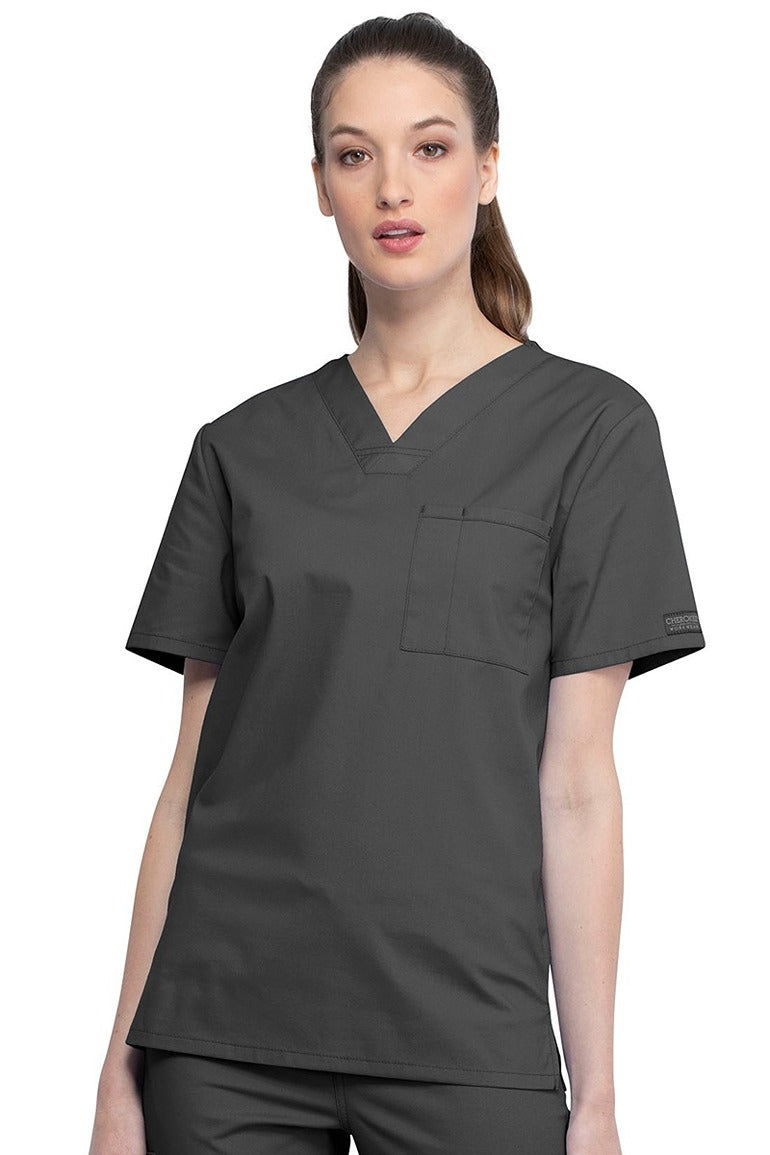 A female Nursing Assistant wearing a Cherokee Unisex Tuckable V-neck Scrub Top in Pewter size Small featuring a unique Poly/Cotton/Spandex blend fabric.