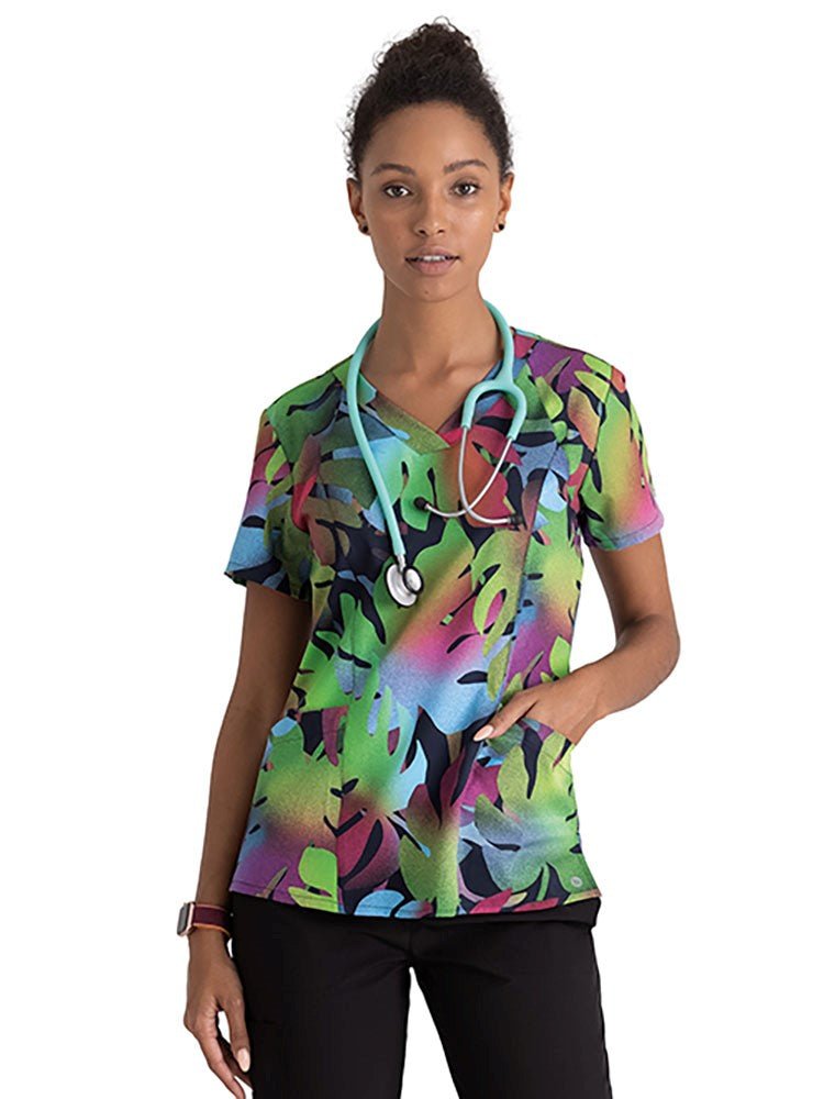 Young dentist wearing a Barco One Women's Print V-Neck Scrub Top in Tropical Breeze with perforated front and back panels.