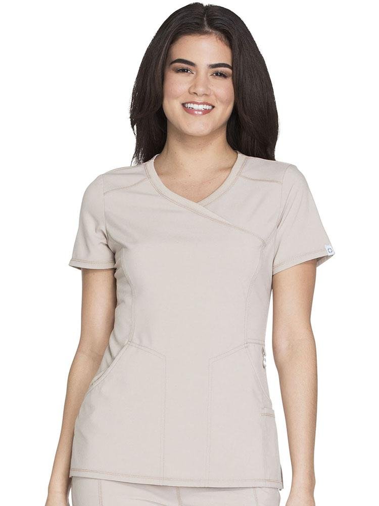 Doctor wearing Cherokee Infinity Women's Antimicrobial Mock Wrap Top in khaki featuring a logo O-ring above left pocket