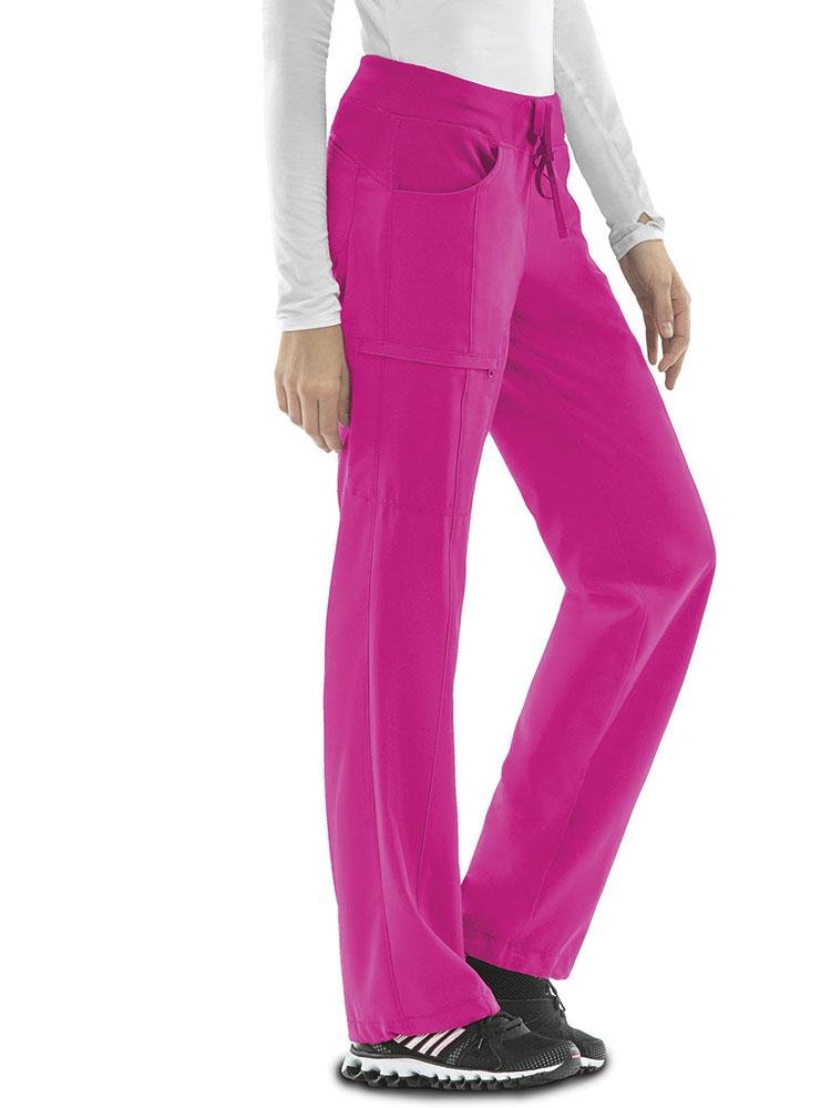 A young female Registered Nurse wearing a Cherokee Infinity Women's Low-Rise Straight Leg Scrub Pant in carmine pink featuring a bungee instrument loop below left pocket.