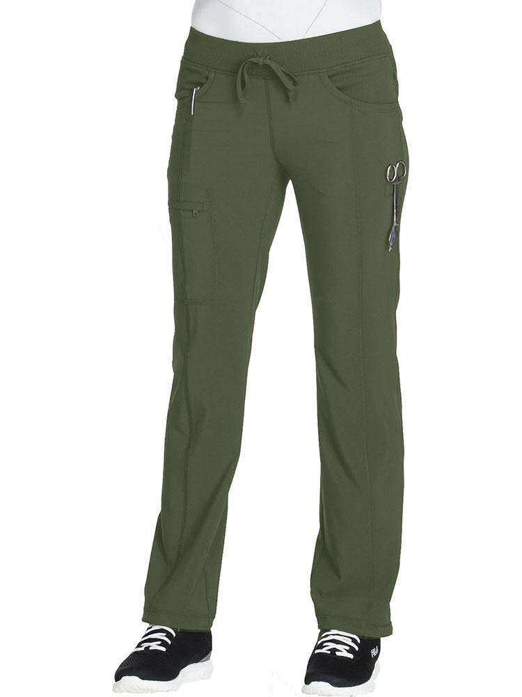A young female Nursing Assistant wearing a Cherokee Infinity Women's Low-Rise Straight Leg Scrub Pant in olive featuring front leg seams & a zip closure cargo pocket.