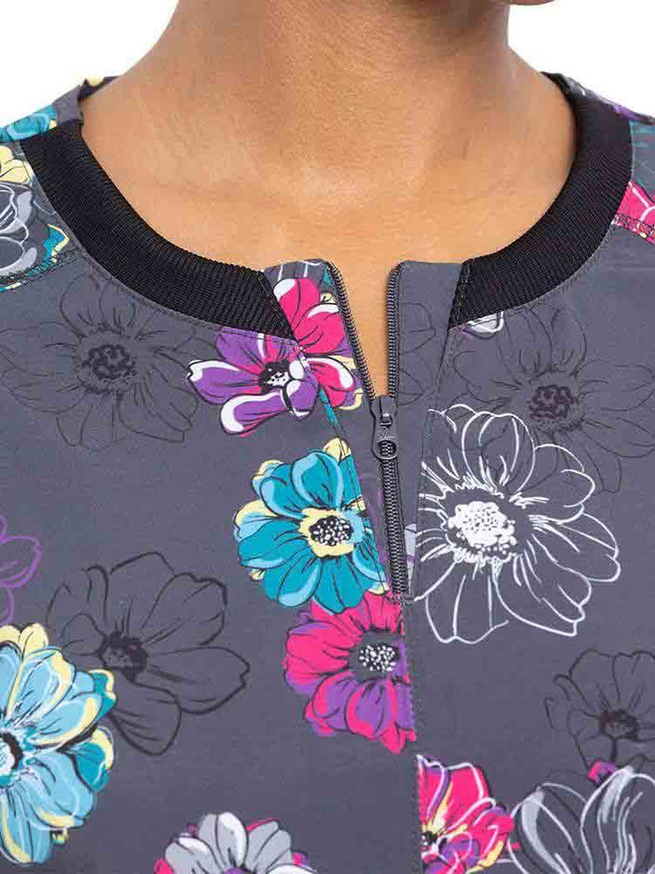 Young nurse wearing a Cherokee Infinity Women's Round Neck Print Top in "Poppin' Floral" featuring a stylish zipper at the wearer's neckline.