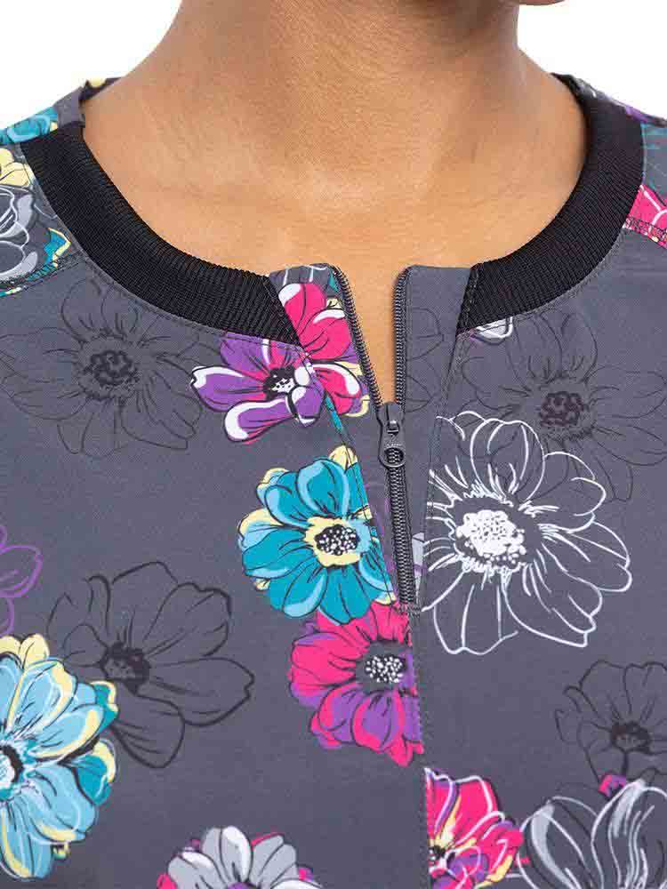 Young nurse wearing a Cherokee Infinity Women's Round Neck Print Top in "Poppin' Floral" featuring a stylish zipper at the wearer's neckline.