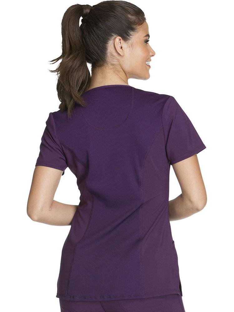 A young female Dietician wearing a Cherokee Infinity Women's Round Neck Scrub Top in Eggplant size XL featuring a rib-knit back panel for additional range of motion on the job.