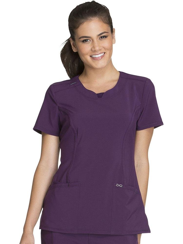 A female Nurse Practitioner wearing a Cherokee Infinity Women's Round Neck Scrub Top in Eggplant size Medium featuring a contemporary fit with a round neckline.