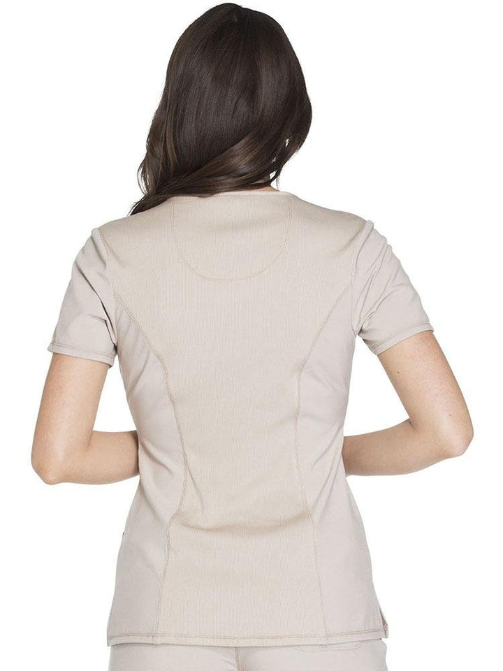 A female Pharmacy Technician wearing a Cherokee Infinity Women's Round Neck Scrub Top in khaki size XS featuring a stretch rib knit back panel for added movement.