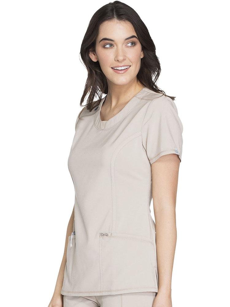 A young female Sonographer wearing a Cherokee Infinity Women's Round Neck Scrub Top in khaki size Large featuring front and back princess seams for a flattering fit.