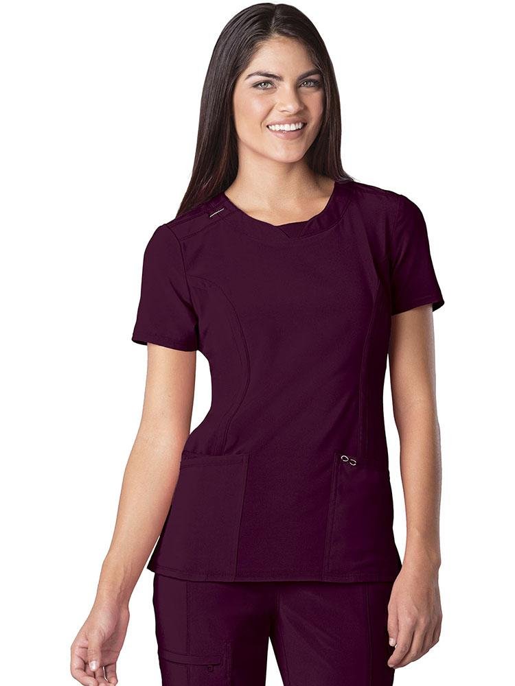 A young female Veterinarian wearing a Cherokee Infinity Women's Round Neck Scrub Top in Wine size Large featuring 2 front patch pockets & 1 interior pocket on the wearer's right side.