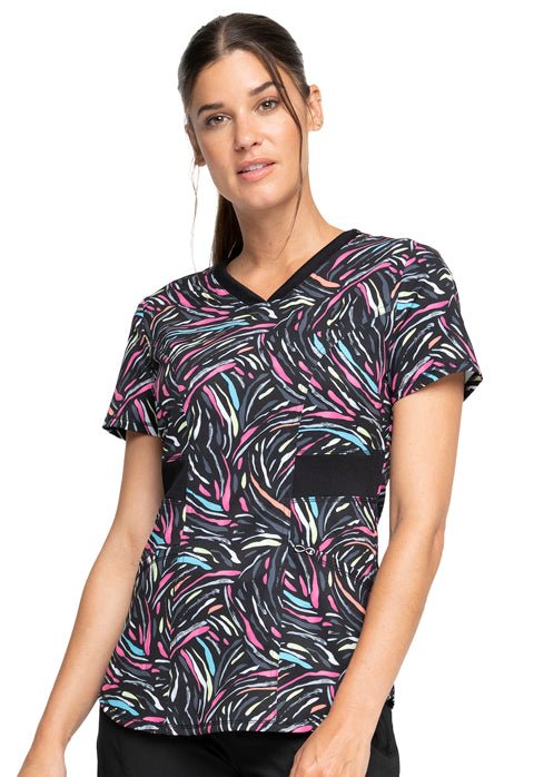 Young woman wearing a Women's V-Neck Print Top from Cherokee Infinity in "Glowing for It" featuring a rounded, v-neckline.