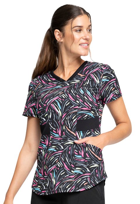 Young woman wearing a Women's V-Neck Print Top from Cherokee Infinity in "Glowing for It" featuring 2 front patch pockets.