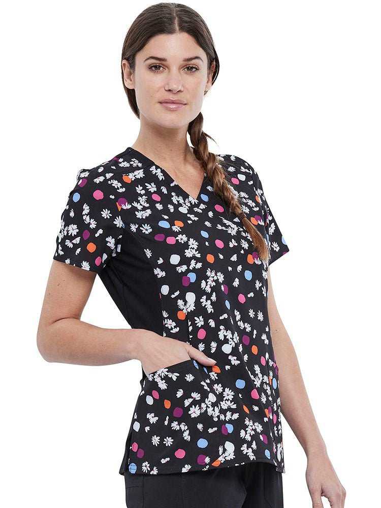 Young nurse wearing a Cherokee Women's Knit Panel Print Top in Polka Dot Petals featuring a cross-hatch dobby stretch fabric.
