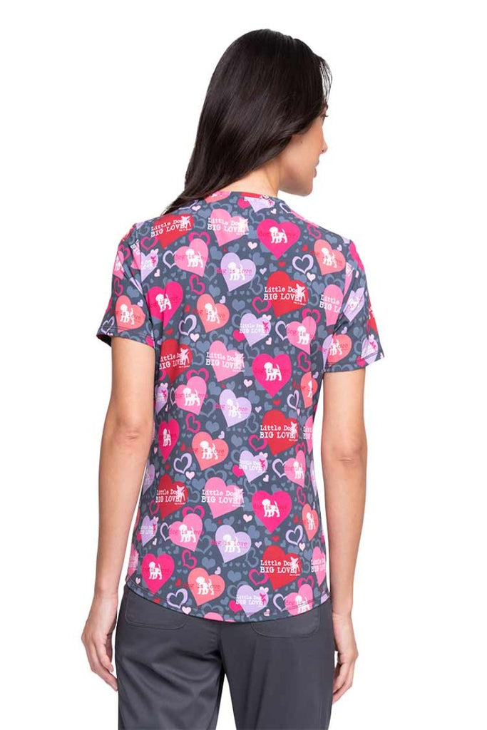 A young female Nursing Assistant wearing a Cherokee Women's V-neck Print Scrub Top ion "Dog is Love" featuring a center back length of 26".