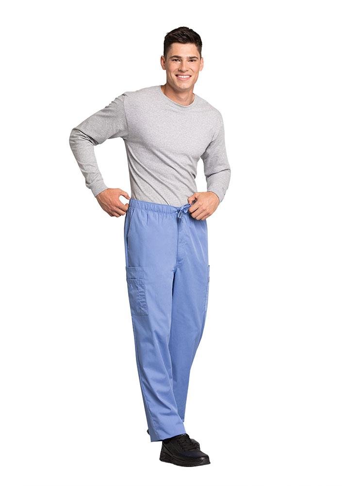 A male Nursing Assistant wearing a Cherokee Workwear Originals Men's Drawstring Cargo Scrub Pant in Ceil size Large featuring 2 front slash pockets & a functional zip fly.