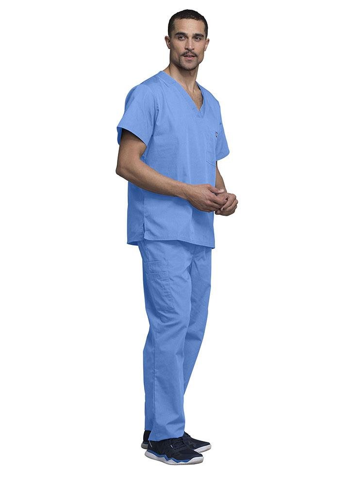 A young male Medical Assistant wearing a Cherokee Workwear Originals Men's Solid V-neck Scrub Top in "Ceil" size 2Xl featuring side vents for additional range of motion throughout the day.
