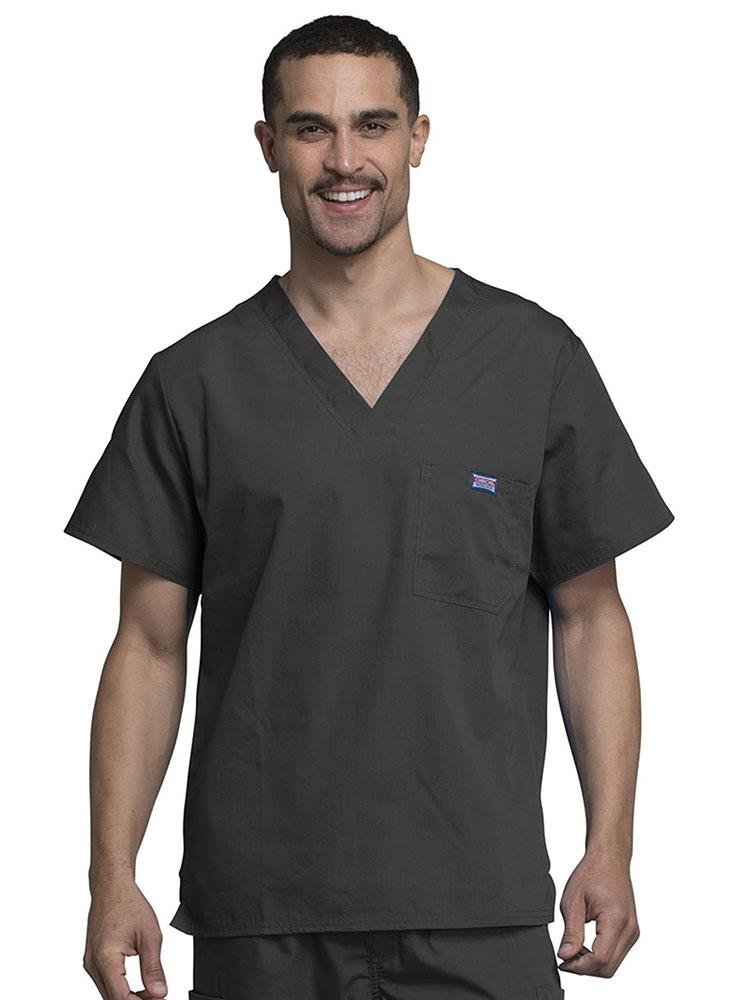 A young male Chiropractor wearing a Cherokee Workwear Originals Men's Solid V-neck Scrub Top in Pewter size 3XL featuring a chests pocket with a pen slot on the wearer's left side.