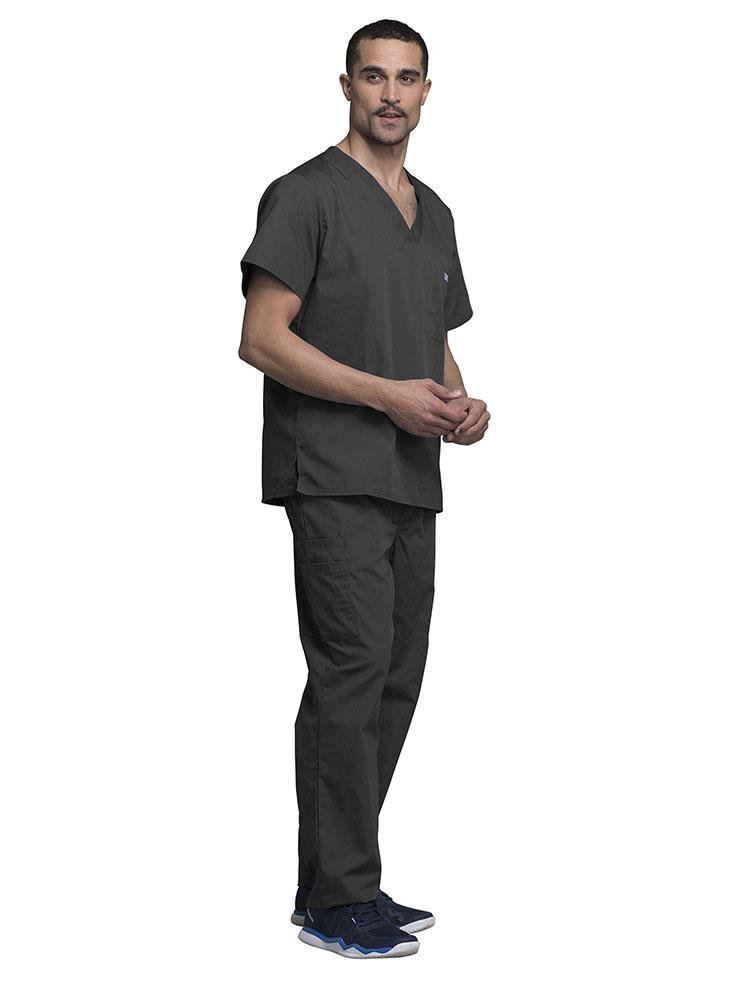 A young male Medical Assistant wearing a Cherokee Workwear Originals Men's Solid V-neck Scrub Top in "Pewter" size 2Xl featuring side vents for additional range of motion throughout the day.