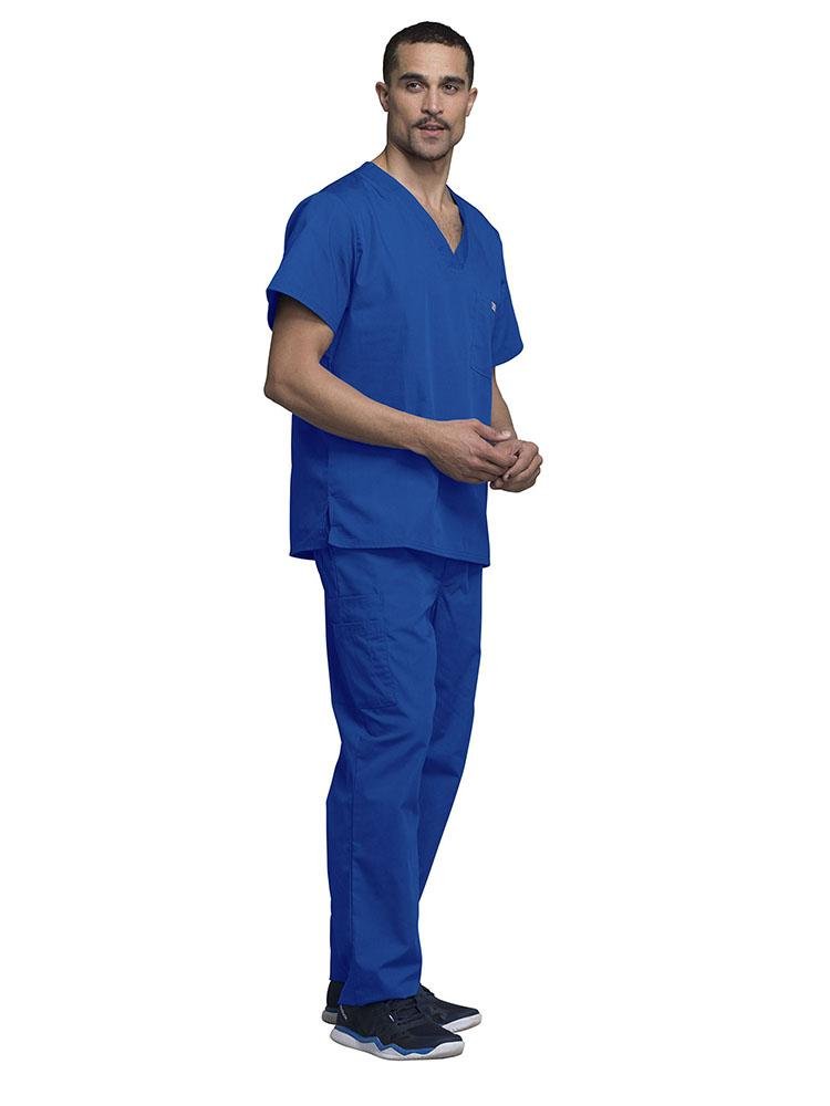 A young male Medical Assistant wearing a Cherokee Workwear Originals Men's Solid V-neck Scrub Top in "Royal" size 2Xl featuring side vents for additional range of motion throughout the day.