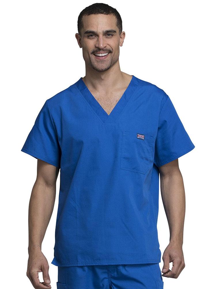 A young male Physician's Assistant wearing a Cherokee Workwear Originals Men's Solid V-neck Scrub Top in Royal size 3XL featuring a chests pocket with a pen slot on the wearer's left side.