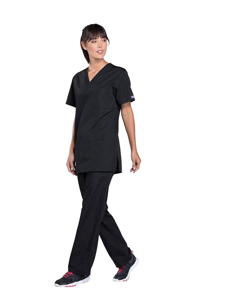 A young female Physical Therapist wearing a Cherokee Workwear Originals Unisex Multi-Pocketed V-neck Scrub Top in Black size XL featuring side slits for additional mobility throughout the day.