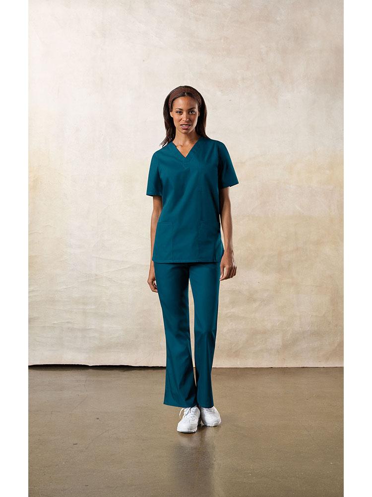 A young female Physical Therapist wearing a Cherokee Workwear Originals Unisex Multi-Pocketed V-neck Scrub Top in Caribbean size XL featuring side slits for additional mobility throughout the day.