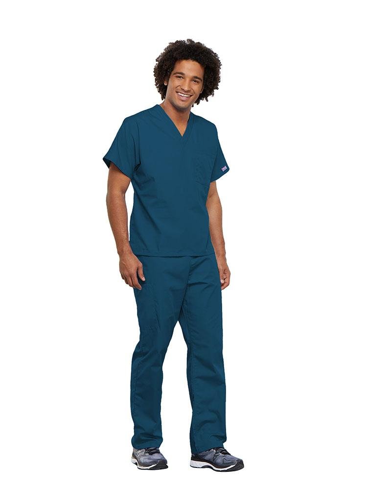 A male Surgical Technician wearing a Cherokee Workwear Originals unisex Single Pocket V-Neck Scrub Top in Caribbean size Small featuring 1 spacious chest pocket.