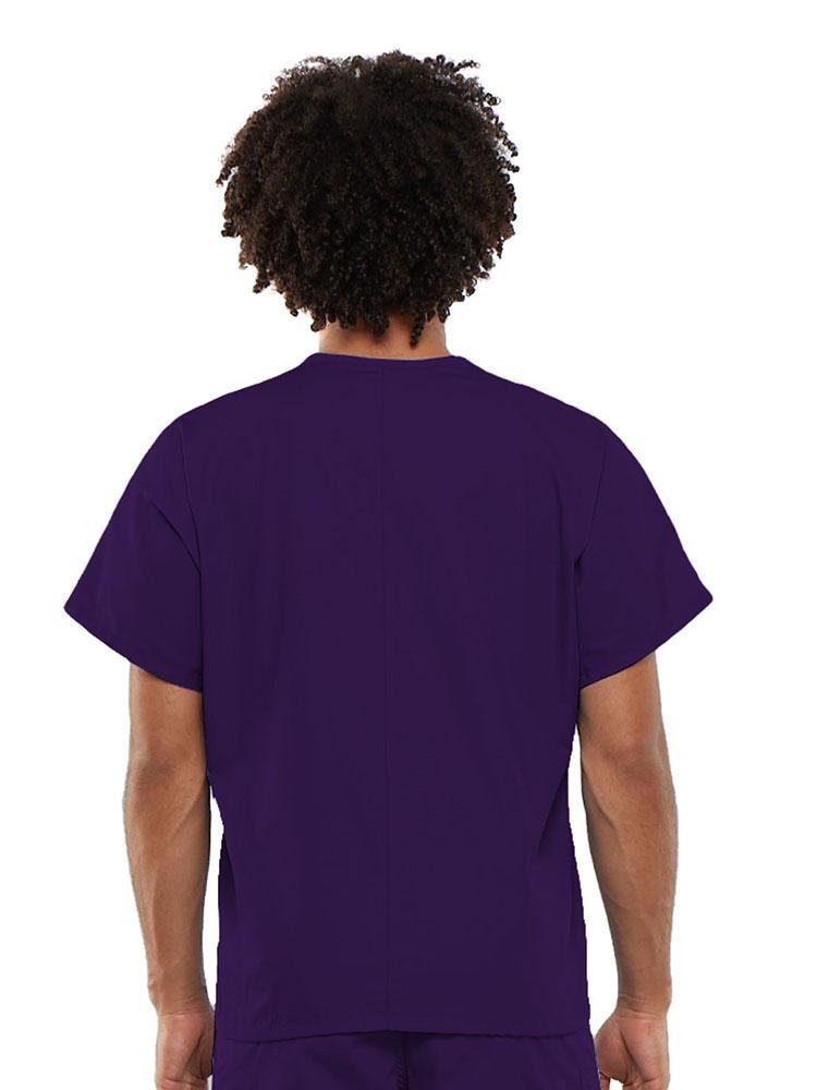 A young male Clinical Laboratory Technician wearing a Cherokee Workwear Originals Unisex Single Pocket V-neck Scrub Top in Eggplant size Large featuring a center back length of 27.5".
