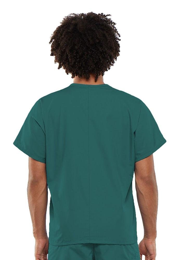 A young male Medical Transcriptionist wearing a Cherokee Workwear Originals Unisex Single Pocket V-neck Scrub Top in Teal size Large featuring a center back length of 27.5".