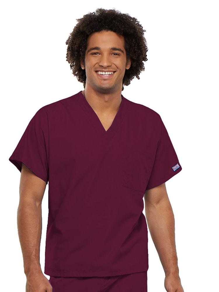 A young male Physician's Assistant wearing a Cherokee Workwear Originals Unisex Single Pocket V-neck Scrub Top in Wine size 4XL featuring short sleeves.