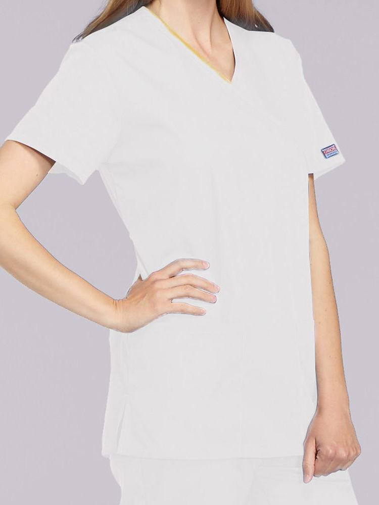 A young female Clinical Laboratory Technician wearing a Cherokee Workwear Originals Women's Mock Wrap Solid Scrub Top in White size XS featuring a 2 front patch pockets.