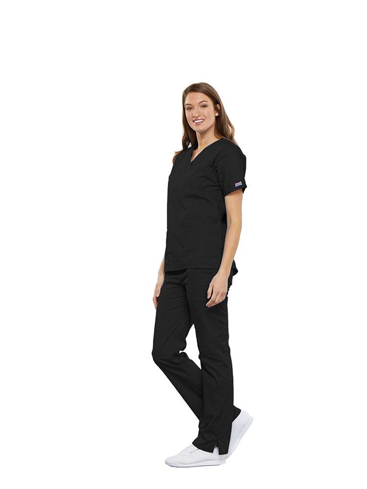 A female Anesthesiologist wearing a Cherokee Workwear Originals women's Multi-Pocketed V-Neck Scrub Top in black size medium featuring side seam vents for additional range of motion throughout the day.