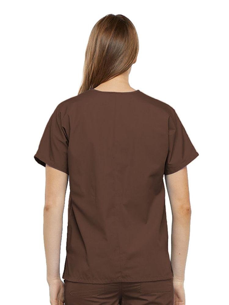A young female Pharmacy Technician wearing a Cherokee Workwear Originals Women's V-neck Scrub Top in Chocolate size Small featuring a center back length of 26.5".