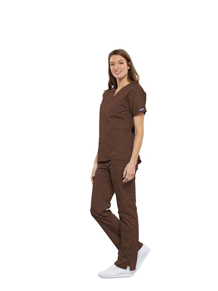 A female Anesthesiologist wearing a Cherokee Workwear Originals women's Multi-Pocketed V-Neck Scrub Top in Chocolate size XS featuring side seam vents for additional range of motion throughout the day.