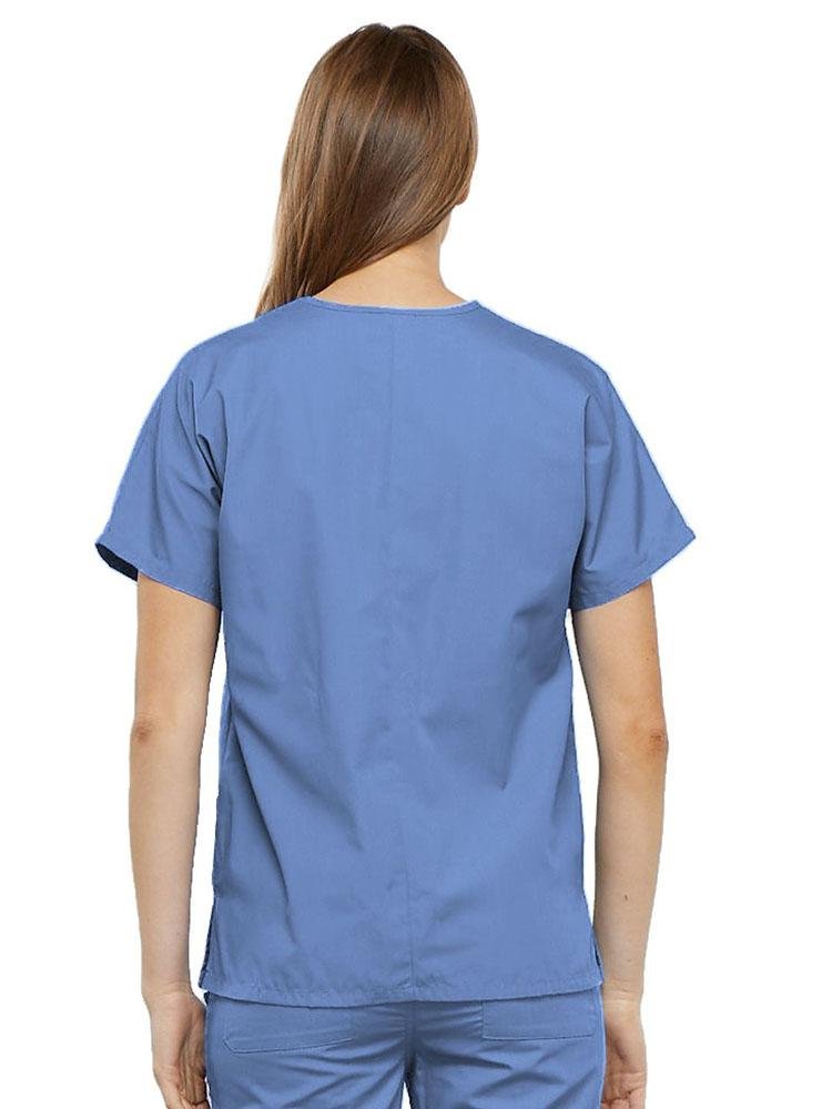 A young female Radiologic Technologist  wearing a Cherokee Workwear Originals Women's V-neck Scrub Top in Ceil size medium featuring a center back length of 26.5".