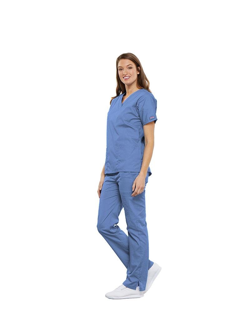 A female Clinical Laboratory Technologist wearing a Cherokee Workwear Originals women's Multi-Pocketed V-Neck Scrub Top in Ceil size Small featuring side seam vents for additional range of motion throughout the day.