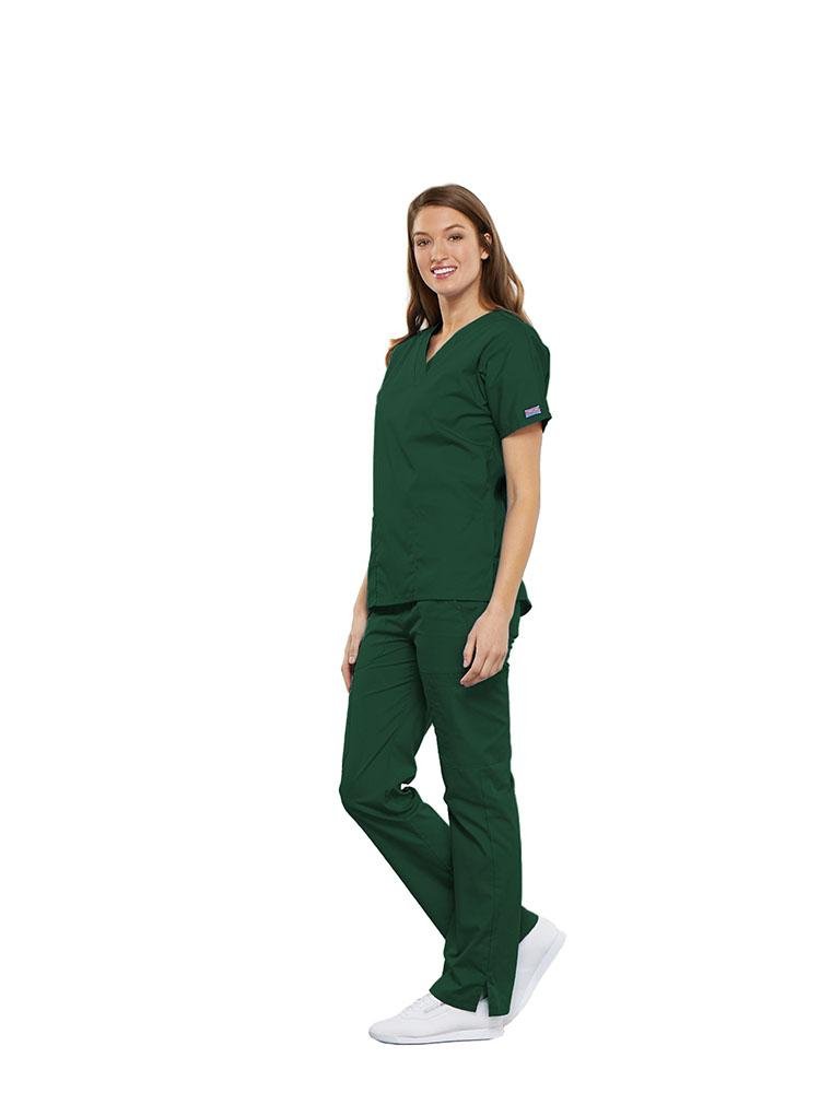 A female Clinical Laboratory Technologist wearing a Cherokee Workwear Originals women's Multi-Pocketed V-Neck Scrub Top in Hunter Green size Large featuring side seam vents for additional range of motion throughout the day.