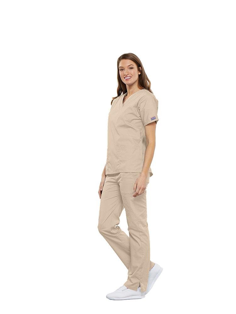 A female Anesthesiologist wearing a Cherokee Workwear Originals women's Multi-Pocketed V-Neck Scrub Top in Khaki size 3XL featuring side seam vents for additional range of motion throughout the day.