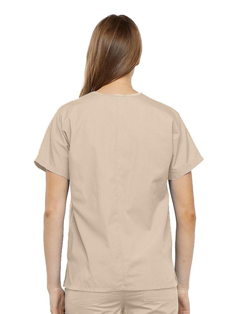 A young female LPN wearing a Cherokee Workwear Originals Women's V-neck Scrub Top in Khaki size medium featuring a center back length of 26.5".
